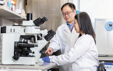 Doctor and student in lab at microscope