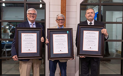Three men holding awards