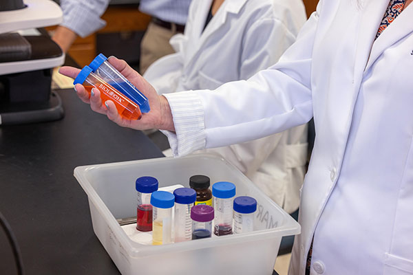 Person in lab coat holding vials