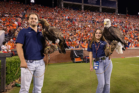 Two people each holding an eagle