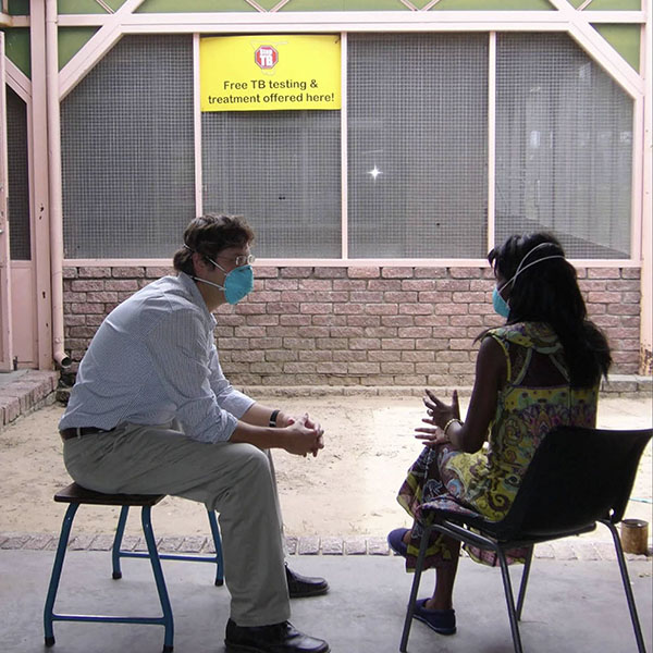 Dr. Nickolas DeLuca speaks with a woman at a tuberculosis clinic.